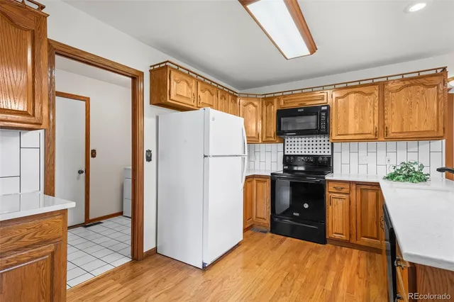 a kitchen with stainless steel appliances granite countertop a refrigerator a stove and a sink with wooden floor