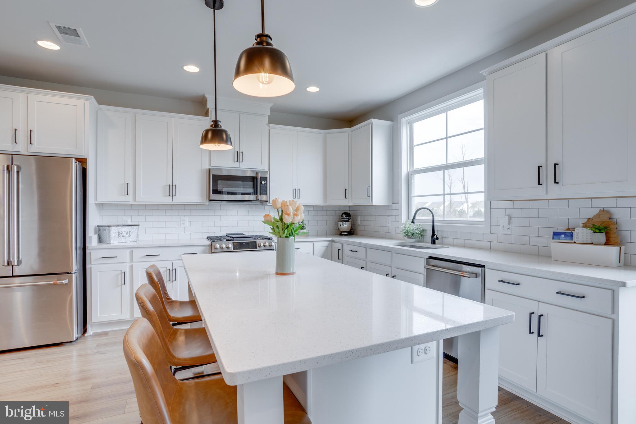 14488 Nebbiolo Drive Gainesville, VA 20155 - Photo 25 of 54 a kitchen with stainless steel appliances granite countertop a stove a refrigerator a sink a stove and white cabinets with wooden floor
