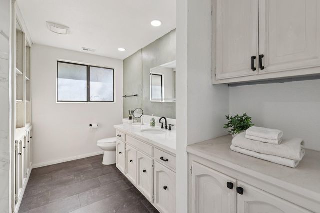 a bathroom with a granite countertop sink a toilet a mirror and shower