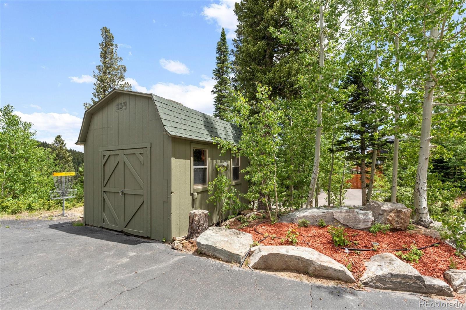 1682 Sinton Road Evergreen, CO 80439 - Photo 37 of 40 a backyard of a house with a fireplace and tree