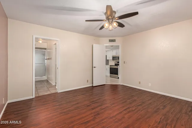 an empty room with wooden floor and ceiling fan