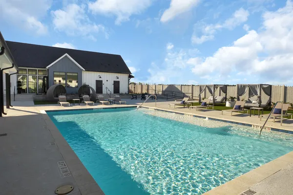 a view of swimming pool with lawn chairs and plants
