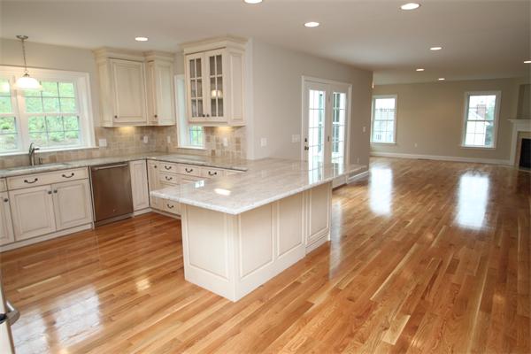 a large kitchen with stainless steel appliances granite countertop a lot of counter space and wooden floors