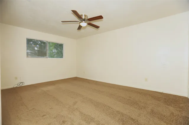 an empty room with a window and a fan