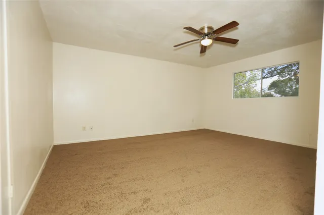 an empty room with a window and a ceiling fan