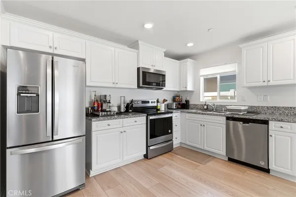 a kitchen with granite countertop a refrigerator stove top oven and sink