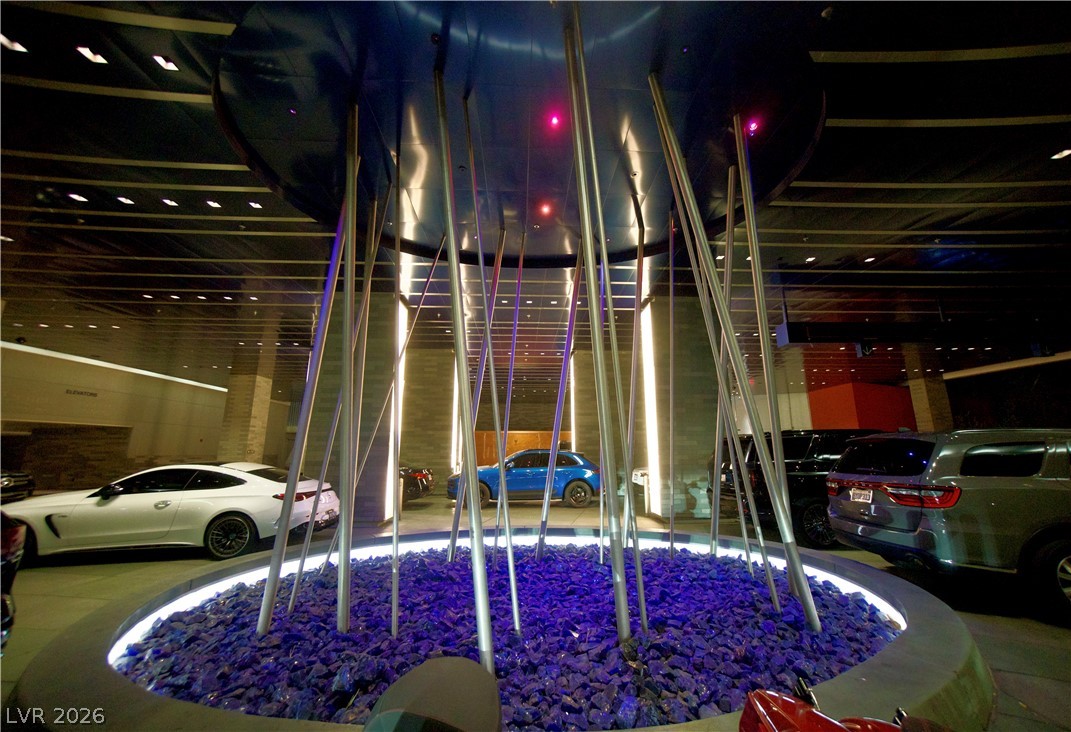 4381 West Flamingo Road, Unit 3616 Las Vegas, NV 89103 - Photo 2 of 29 A stylish, well-lit parking area features an artistic central fountain with luminous blue stones.