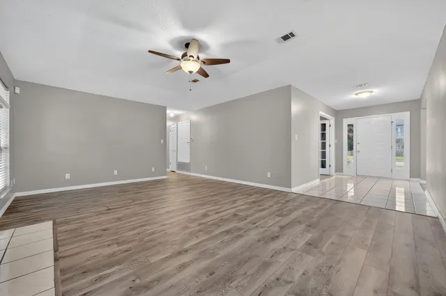 a view of empty room with wooden floor and fan