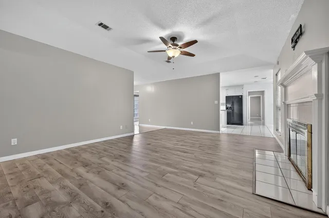 an empty room with wooden floor windows and a fireplace