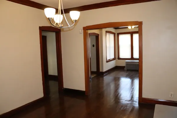 a view of a room with wooden floor chandelier and windows