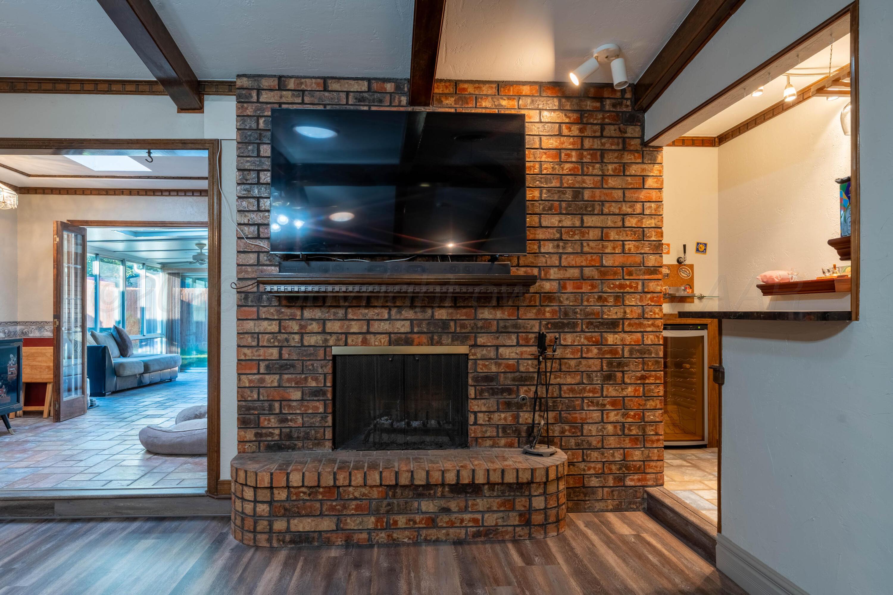 6606 Drexel Road Amarillo, TX 79109 - Photo 14 of 44 a living room with a fireplace a flat screen tv and a floor to ceiling window