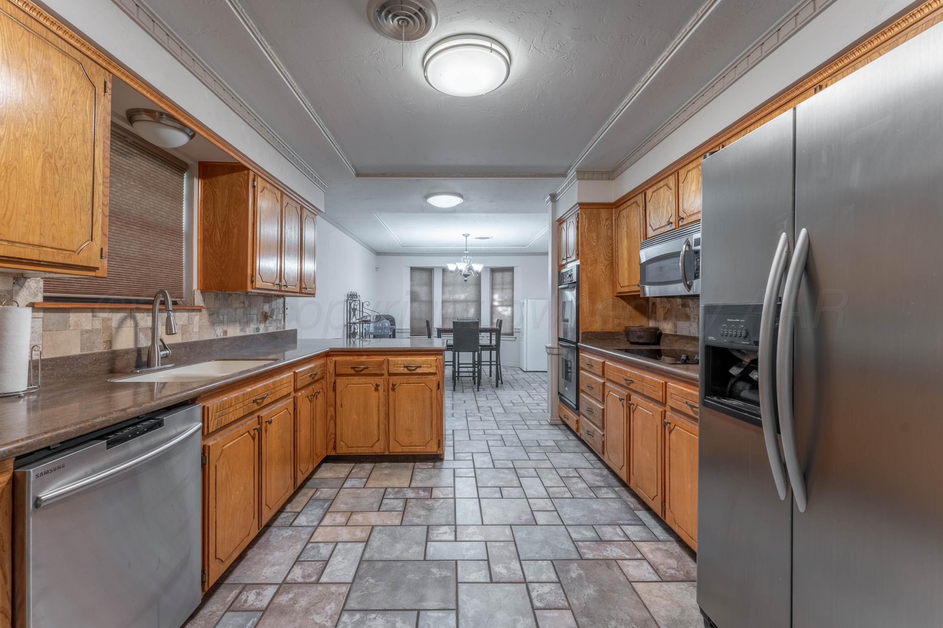 6606 Drexel Road Amarillo, TX 79109 - Photo 15 of 44 a large kitchen with stainless steel appliances granite countertop a sink counter space cabinets and a large window