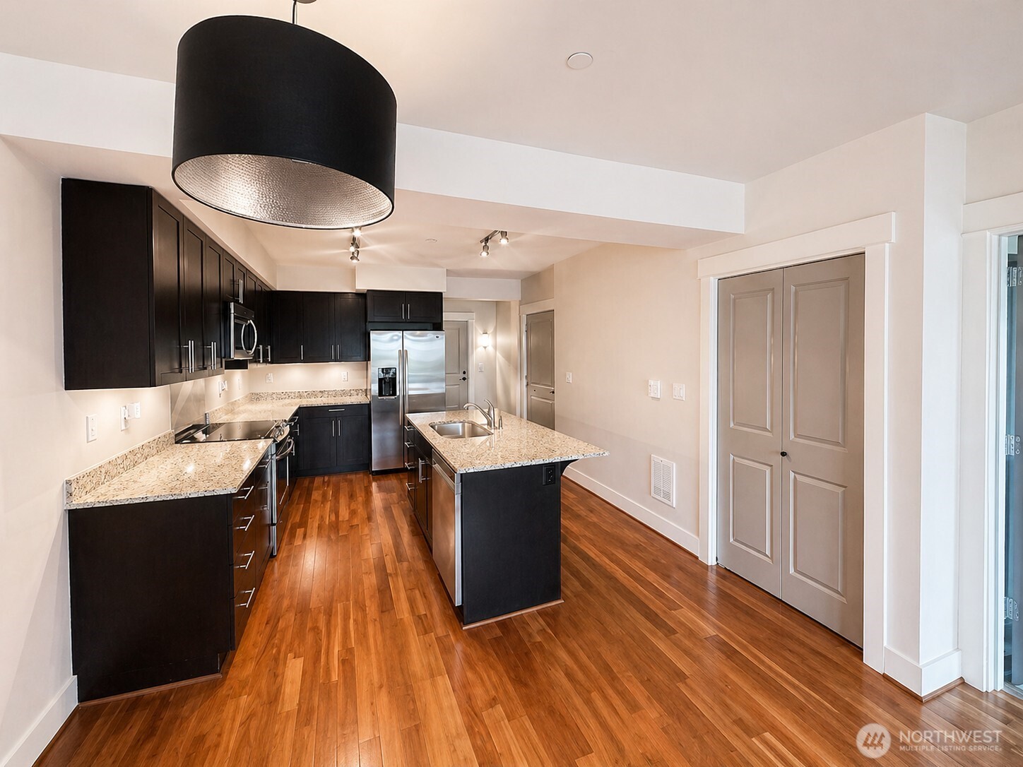 699 John Street, Unit 515 Seattle, WA 98109 - Photo 9 of 26 a living room with stainless steel appliances kitchen island granite countertop a sink dishwasher and a black stove with wooden floor