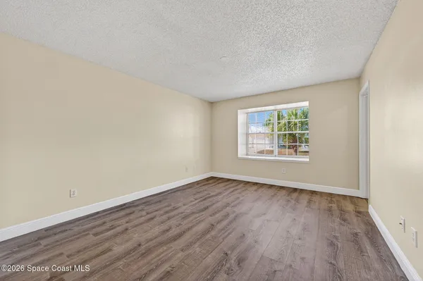 a view of an empty room with wooden floor and window