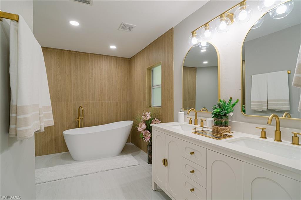 131 25th Street Southwest Naples, FL 34117 - Photo 27 of 50 a bathroom with a double vanity sink a mirror and a bathtub