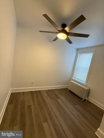 an empty room with a ceiling fan and wooden floor