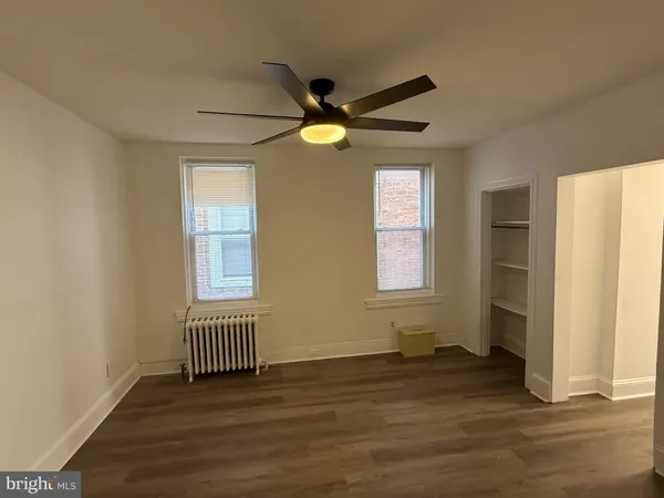 a view of an empty room with window and wooden floor