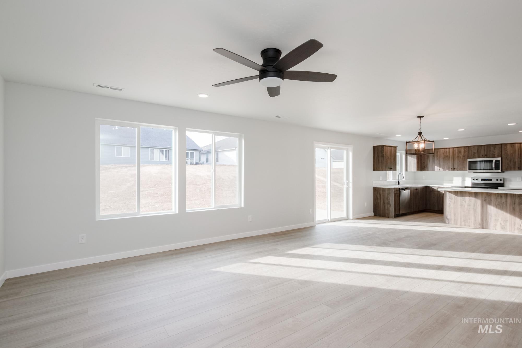 13697 Inman Court Caldwell, ID 83607 - Photo 11 of 23 Unfurnished living room featuring hanging lights, a ceiling fan, and light wood-type flooring