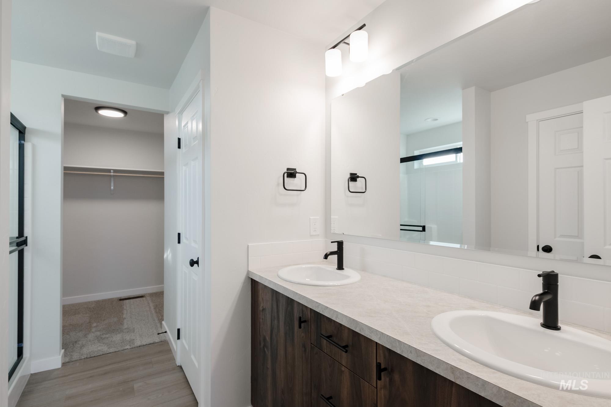13697 Inman Court Caldwell, ID 83607 - Photo 16 of 23 Full bath featuring a shower stall, a spacious closet, double vanity, and light wood finished floors