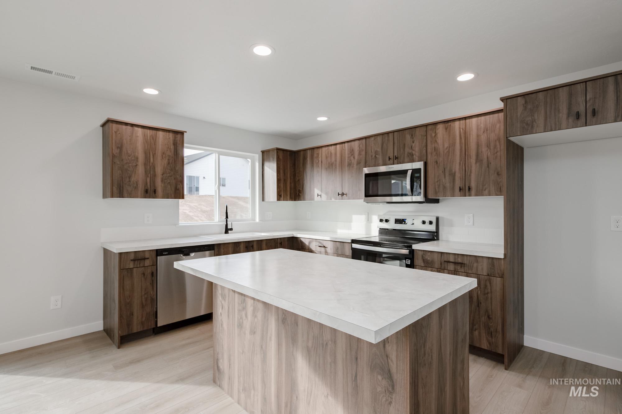 13697 Inman Court Caldwell, ID 83607 - Photo 3 of 23 Kitchen with a kitchen island, stainless steel appliances, light countertops, light wood-style floors, and recessed lighting