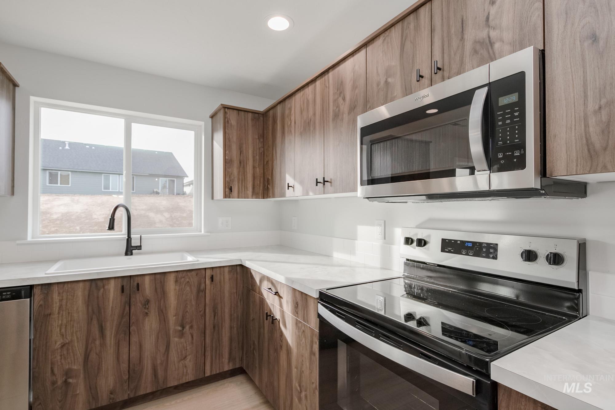 13697 Inman Court Caldwell, ID 83607 - Photo 7 of 23 Kitchen with stainless steel appliances, light countertops, wood finish cabinetry, recessed lighting, and modern cabinets
