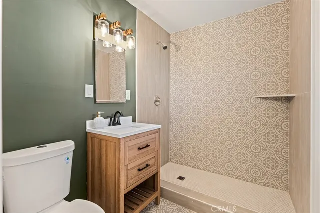 a bathroom with a granite countertop sink a toilet and shower