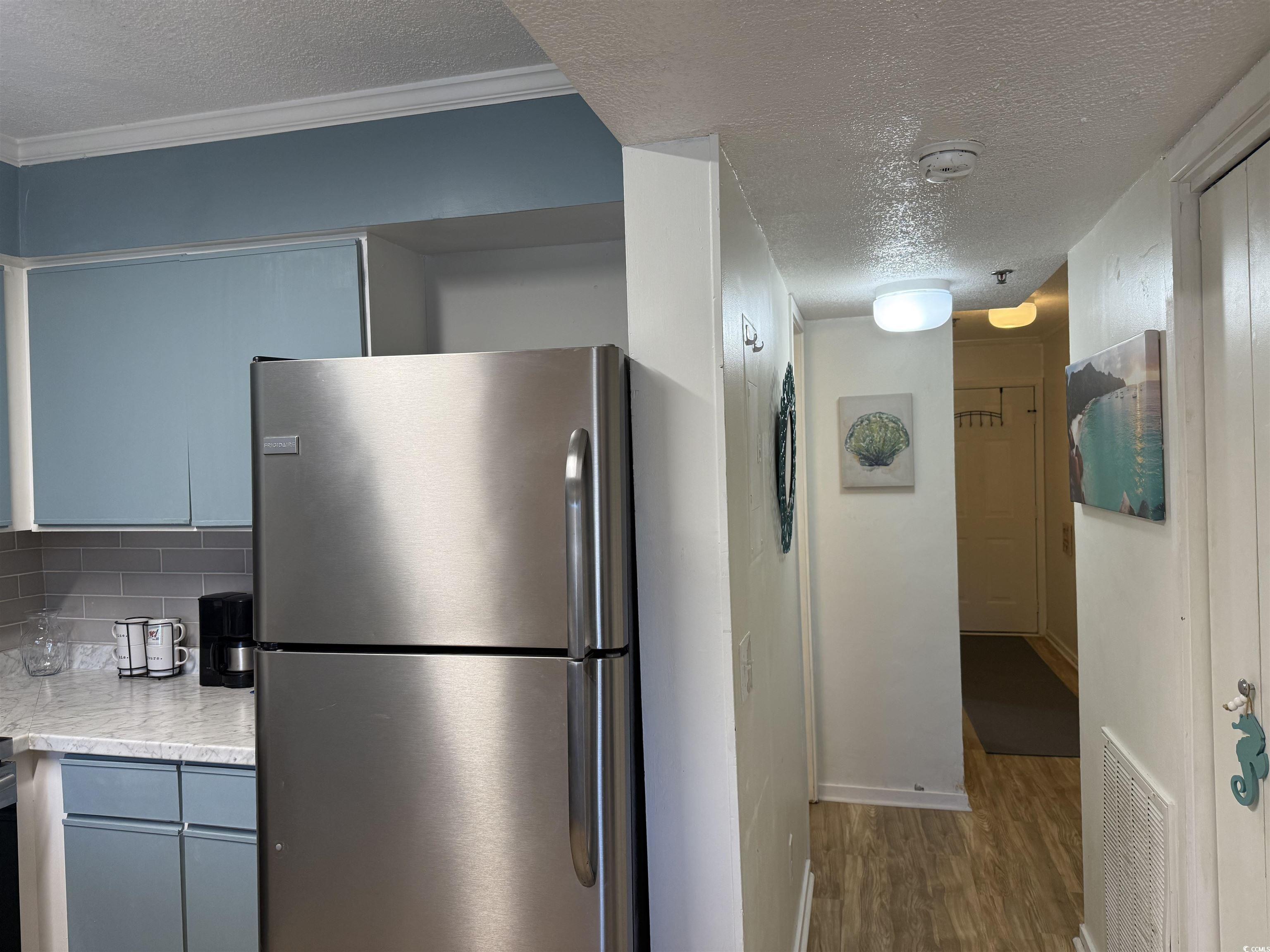 4350 Intercoastal Drive, Unit INTERCOASTAL VILLAGE UNI Little River, SC 29566 - Photo 19 of 21 Kitchen featuring a textured ceiling, freestanding refrigerator, light countertops, tasteful backsplash, and dark wood-type flooring