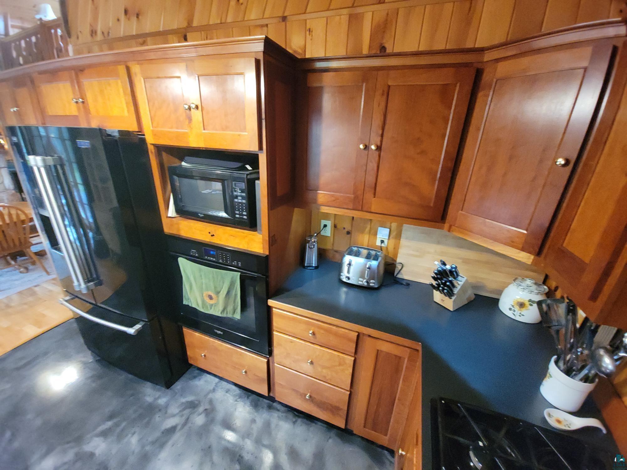 181 Linnell Road Grand Marais, MN 55604 - Photo 43 of 77 Wood-finish cabinetry, dark countertops, integrated wall oven, built-in microwave, and wood-finish flooring