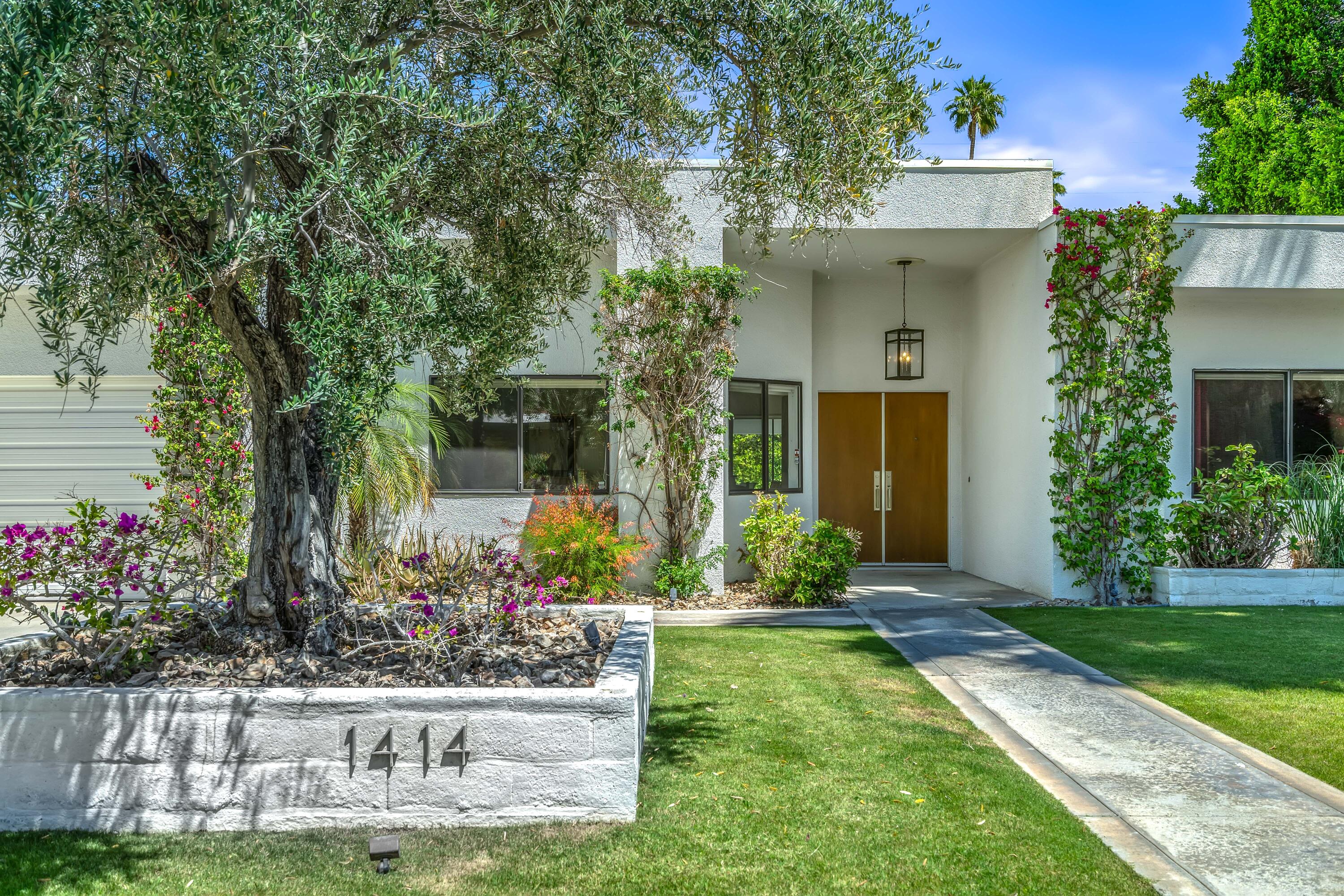 a front view of a house with a yard and potted plants