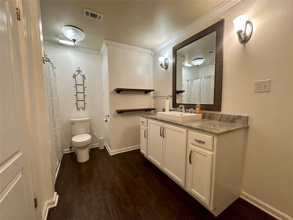 2734 Mildred Street Waco, TX 76706 - Photo 15 of 32 Full bath with curtained shower, vanity, crown molding, and dark wood-type flooring