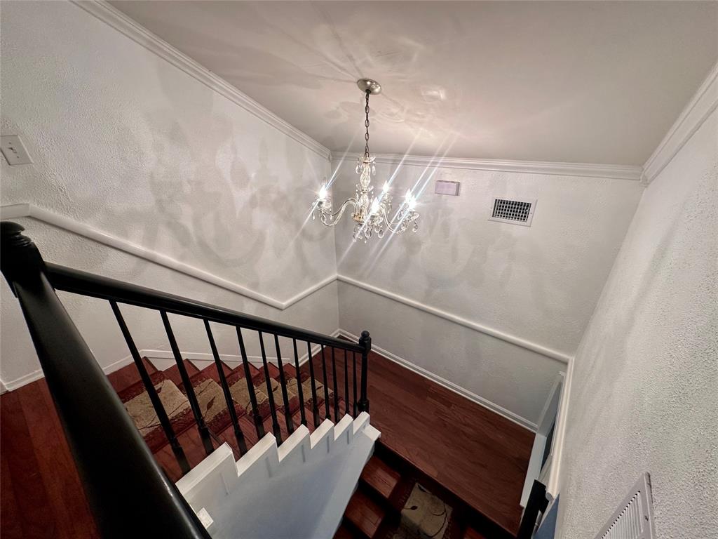 2734 Mildred Street Waco, TX 76706 - Photo 17 of 32 Staircase featuring ornamental molding, a textured wall, wood finished floors, and hanging lights