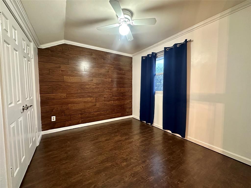 2734 Mildred Street Waco, TX 76706 - Photo 22 of 32 Upstairs bedroom featuring wooden walls, crown molding, dark wood-style floors, lofted ceiling, and ceiling fan
