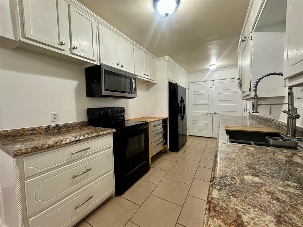 2734 Mildred Street Waco, TX 76706 - Photo 8 of 32 Kitchen with black appliances, white cabinetry, and light tile patterned floors