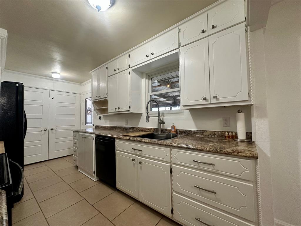 2734 Mildred Street Waco, TX 76706 - Photo 10 of 32 Kitchen with dark countertops, white cabinetry, black appliances, and light tile patterned floors