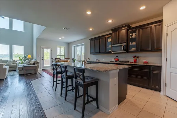 a kitchen with stainless steel appliances granite countertop a stove top oven a sink dishwasher a dining table and chairs with wooden floor