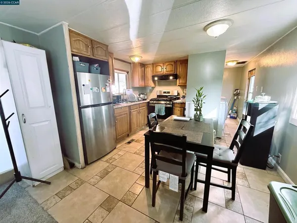 a kitchen with stainless steel appliances a refrigerator a stove a sink dishwasher and a dining table with wooden floor