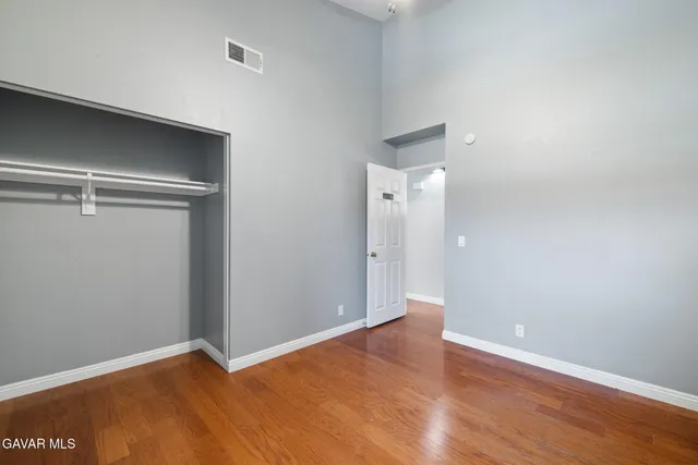 a view of an empty room with wooden floor and closet