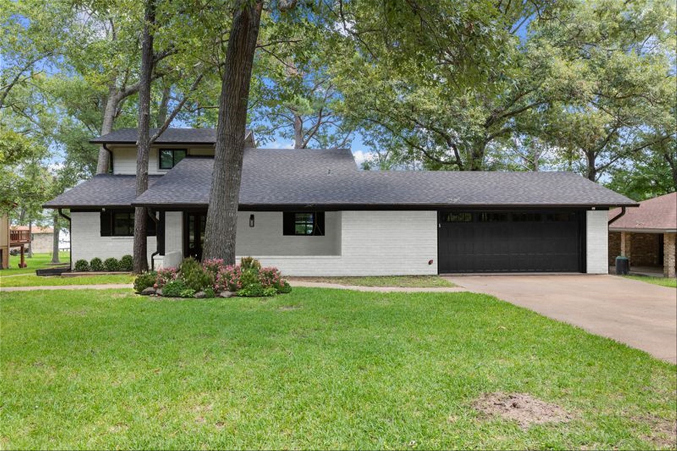 a front view of a house with a garden and trees