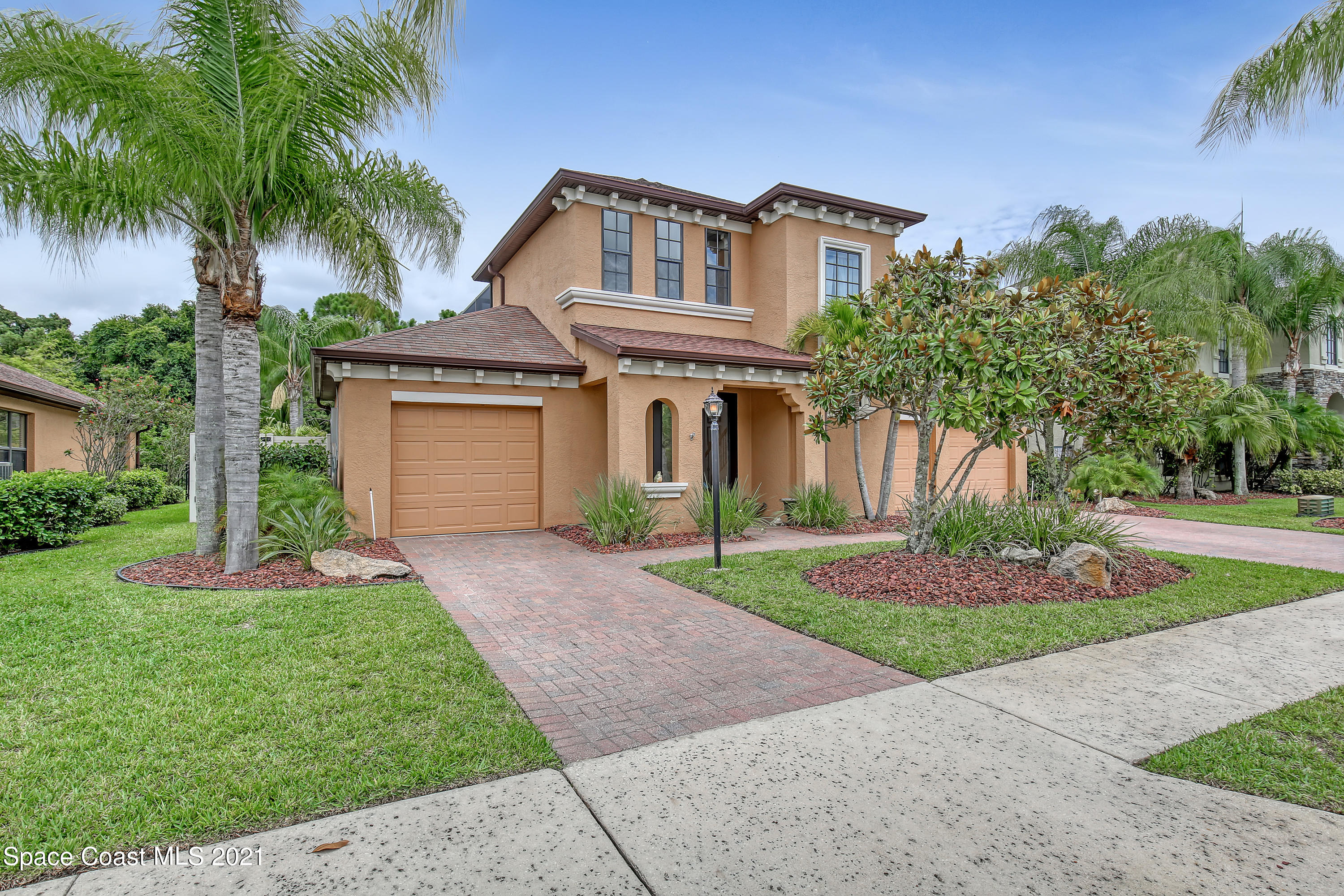a front view of a house with a garden and palm trees