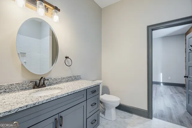 a bathroom with a granite countertop toilet a sink and a mirror