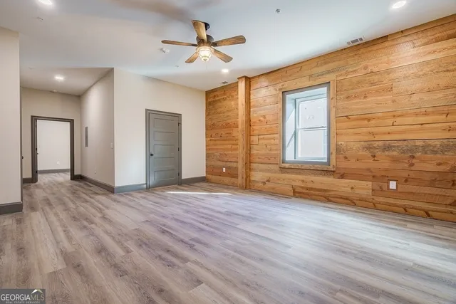 a view of an empty room with a window and wooden floor