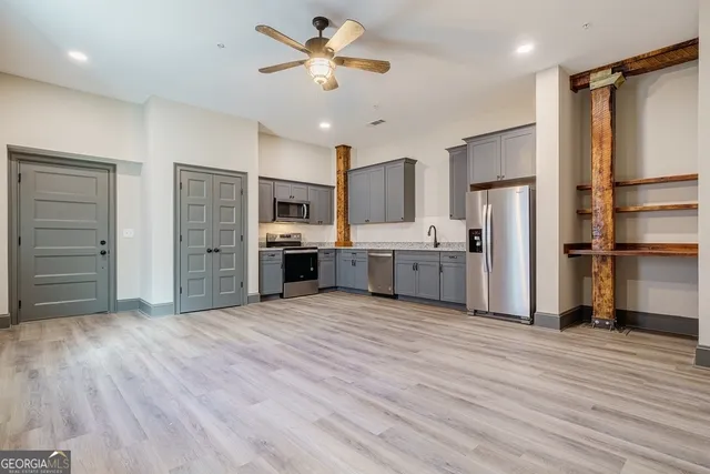 a view of kitchen with stainless steel appliances wooden floor and window
