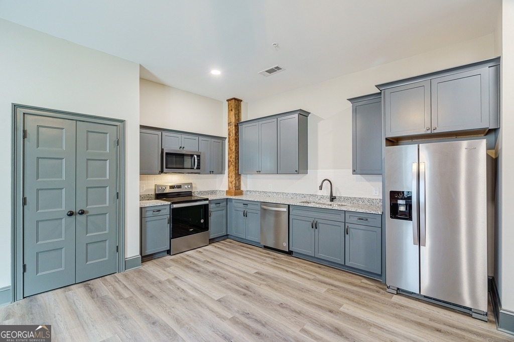 34 Depot Street, Unit 11 Hartwell, GA 30643 - Photo 7 of 21 a large kitchen with cabinets stainless steel appliances and a wooden floor