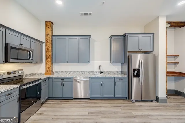 a kitchen with stainless steel appliances granite countertop a refrigerator stove and sink