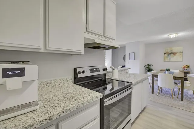 a kitchen with stainless steel appliances granite countertop a stove white cabinets a sink and dishwasher
