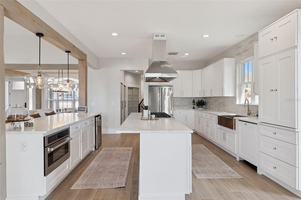 9126 Lake Coventry Court Gotha, FL 34734 - Photo 15 of 76 a large kitchen with stainless steel appliances granite countertop a stove top oven a sink dishwasher and white cabinets with wooden floor