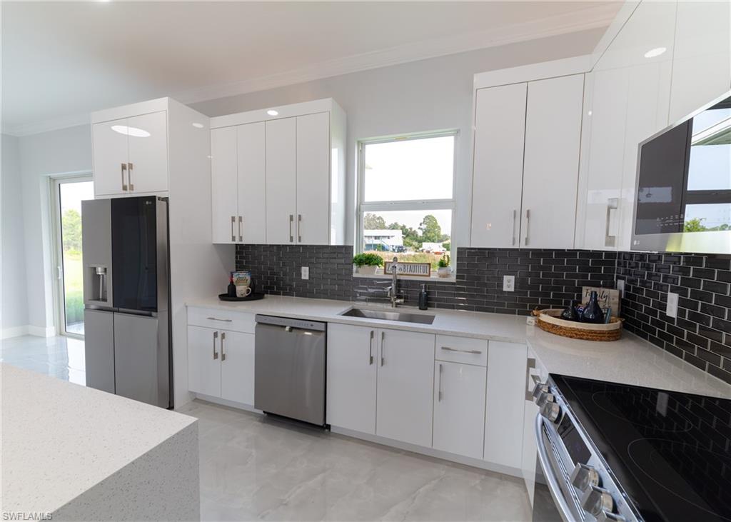 3408 12th Street Southwest Lehigh Acres, FL 33976 - Photo 5 of 47 a kitchen with white cabinets and appliances