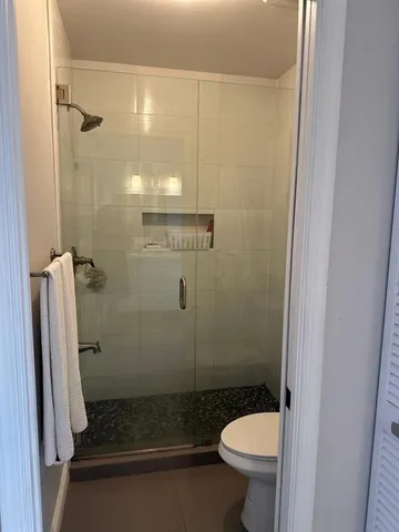 a bathroom with a granite countertop toilet and a shower