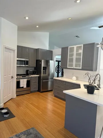 a kitchen with stainless steel appliances wooden floor sink and wooden cabinets
