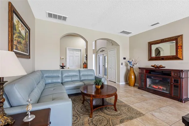a living room with stainless steel appliances furniture a rug and a kitchen view